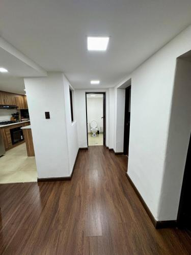 an empty living room with white walls and wood floors at Maravilloso departamento en Azogues in Azogues