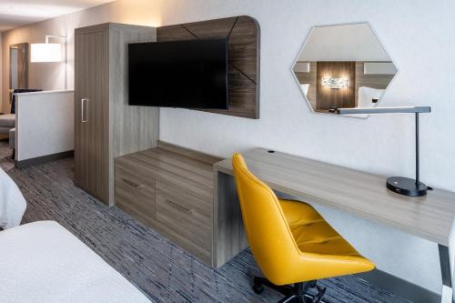 a hotel room with a desk and a yellow chair at Holiday Inn Express & Suites Dewitt - Syracuse by IHG in East Syracuse