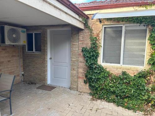 a brick house with a white door and ivy at Lovely granny flat in Perth