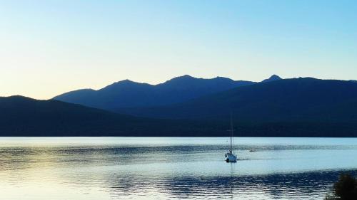a boat on a lake with mountains in the background at Anchorage Motel Apartments in Te Anau