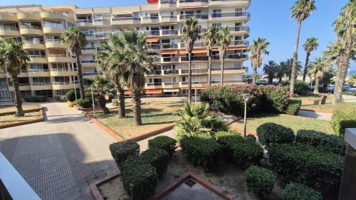 ein großes Apartmenthaus mit Palmen und Büschen in der Unterkunft Studio au pied de l'eau in Canet-en-Roussillon