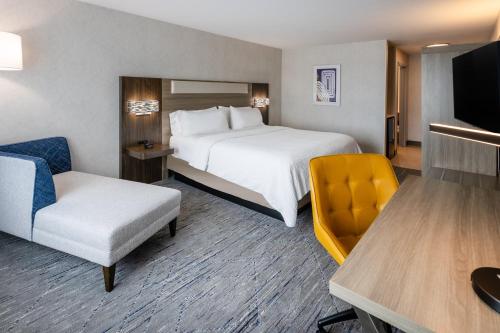 a hotel room with a bed and a chair at Holiday Inn Express & Suites Dewitt - Syracuse by IHG in East Syracuse