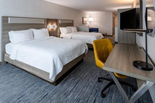 a hotel room with two beds and a desk at Holiday Inn Express & Suites Dewitt - Syracuse by IHG in East Syracuse