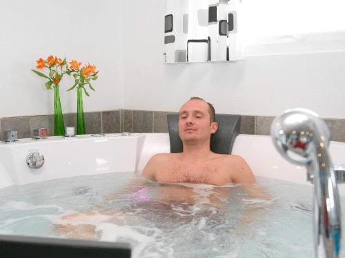 ロッケンにあるLuxury Pool Retreat - By Traum Ferienwohnungenの洗面台のある浴槽に座っている男性