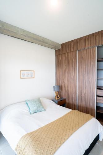 a bedroom with a bed and a wooden wall at Apartamento Anuva con Parking, Alberca y SkyView in Guadalajara
