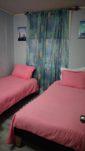 two beds in a room with pink sheets at Departamento central 3D 1b estacionamiento factura in Chillán