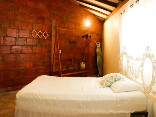 a bed in a room with a brick wall at Dulce Vida - Casa con piscina a 200 mts de la Playa Punta Chame in Punta Chame
