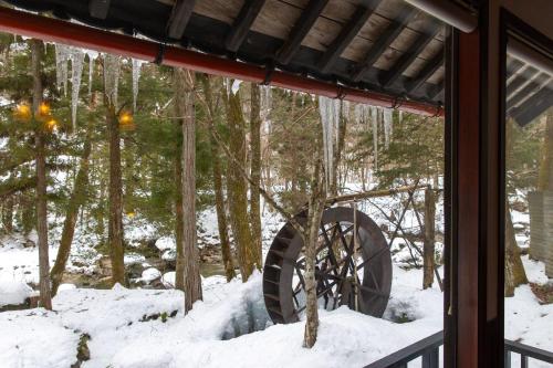 a window of a house with snow and a wheel at Wanosato in Takayama