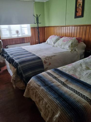 two beds sitting in a bedroom with a window at Hostal Patagonico in Punta Arenas