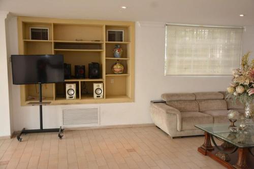 a living room with a couch and a flat screen tv at Casa Cristales Oeste de Cali in Cali