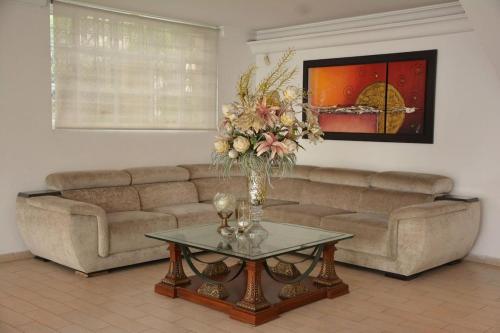a living room with a couch and a table with a vase of flowers at Casa Cristales Oeste de Cali in Cali