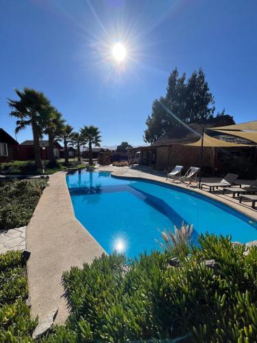a large blue swimming pool with chairs and the sun at Hotel El Bramador in Copiapó