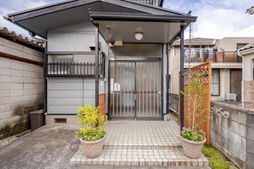 a garage with two potted plants in front of it at Small House Near Narita Airport in Shisui