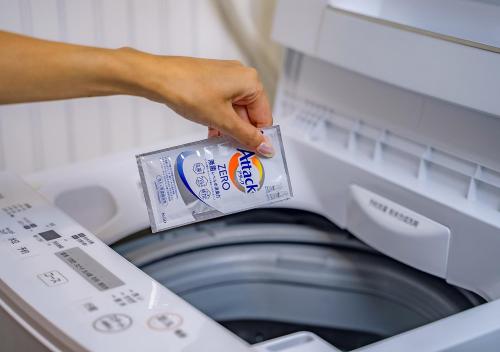 a person is putting a package in a washing machine at Hotel California Miyakojima Resort in Miyako Island