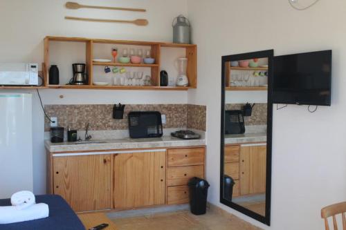 a kitchen with wooden cabinets and a flat screen tv at Pousada Village Gostoso in São Miguel do Gostoso