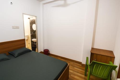 a bedroom with a bed and two green chairs at Residence inn in Dīgha