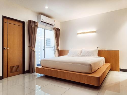 a bedroom with a bed with a wooden frame and a window at Laksika Place Khao Rang in Phuket