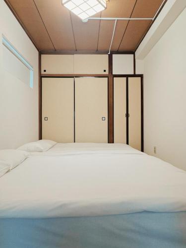 a bedroom with a large white bed with doors at LoveTokyo Easy Access Nezu Sunset House 根津駅徒歩1分 エレベーター 上野 谷中銀座 根津神社 東京大学 新宿 渋谷 銀座 築地 原宿近い in Tokyo