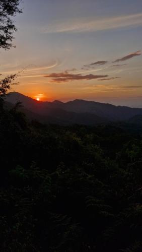 a sunset with the sun setting over the mountains at Mountain Cabin, Minca in Santa Marta