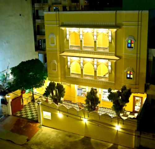 a yellow building with a balcony with lights at Toshina Haveli in Jaipur