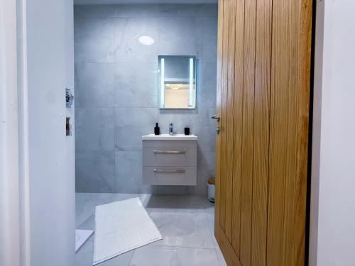 a bathroom with a sink and a wooden door at Elegant 1 bed flat, Sleeps 4, Free parking, Pet friendly, Pudsey, Leeds in Pudsey