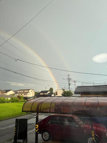 a rainbow in the sky with a car parked on a street at Azumi Holiday House in Azumino