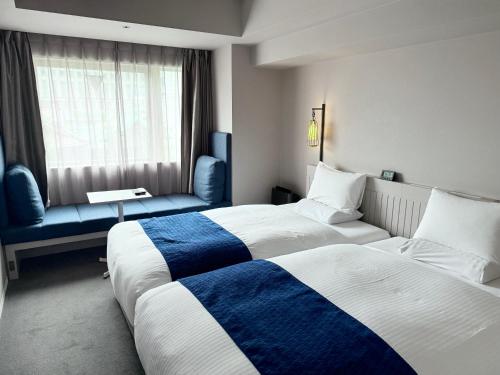 a hotel room with two beds and a couch at HOTEL TORIFITO KANAZAWA in Kanazawa