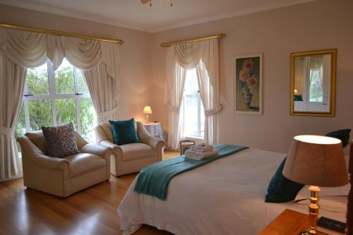 a bedroom with a large bed and a couch and chairs at Bell Rosen Guest House in Bellville