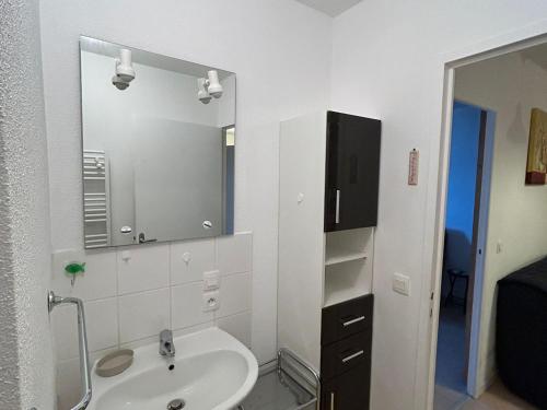 ein weißes Badezimmer mit Waschbecken und Spiegel in der Unterkunft Appartement Sud avec Terrasse et Garage à Super Besse - FR-1-814-96 in Besse-et-Saint-Anastaise