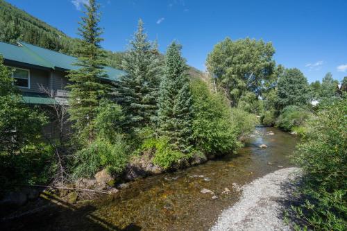 a river next to a house with trees at Mountainside Inn 208 by Alpine Lodging Telluride in Telluride