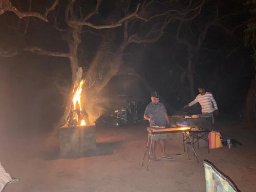 a group of men sitting around a fire at night at Glossy Lake View in Hambantota