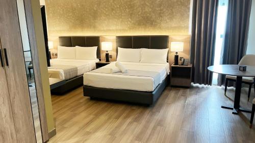 a hotel room with two beds and a table at Vibe Hotel Alabang in Manila