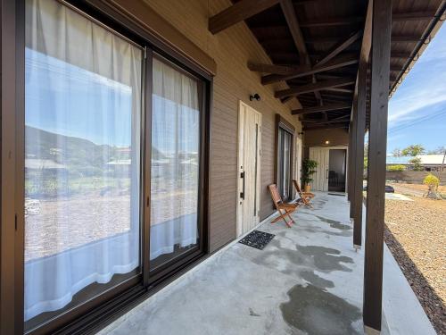 an empty porch with large windows and a chair at Guesthouseあいみ in Amami