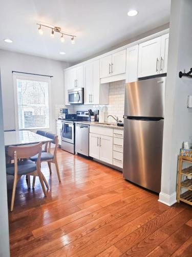 a kitchen with a table and a stainless steel refrigerator at 4 Minutes to UNC - 7 Minutes to Carrboro - En-Suite Bathrooms in Chapel Hill