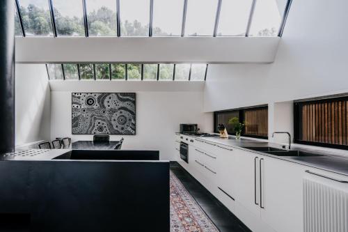 a kitchen with white cabinets and a large window at Alkina Lodge Namu in Wattle Hill