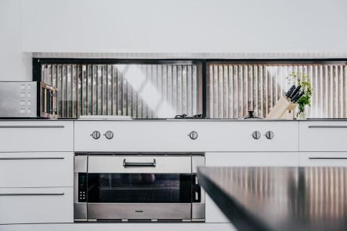 a kitchen with a stove and a microwave at Alkina Lodge Namu in Wattle Hill