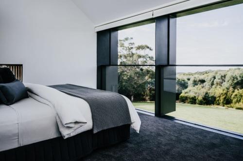a bedroom with a bed and a large window at Alkina Lodge Namu in Wattle Hill