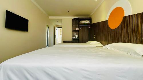 a bedroom with two beds and a flat screen tv at Shanghai Zhongan Hotel Xizang North Road Subway Station Branch in Shanghai