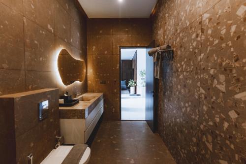 a bathroom with a toilet and a stone wall at AMO Residences in Canggu