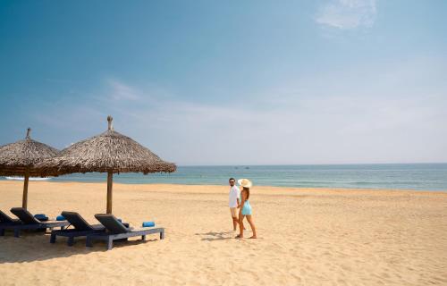 a man and a woman standing on the beach at Hoi An Royal Beachfront Villas in Dien Ban