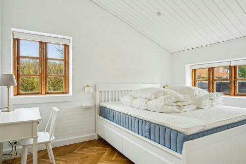 Un dormitorio blanco con una cama, un escritorio y ventanas. en Modern Holiday Home Between Skagen Town And Forest, en Skagen