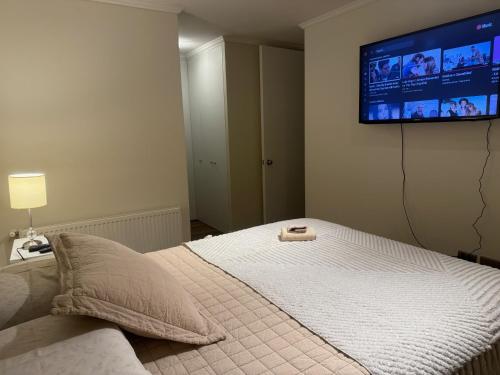 a bedroom with a bed with a flat screen tv on the wall at DPTO frente MALL-AEROPUERTO, CONCEPCION in Concepción