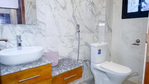 a white bathroom with a sink and a toilet at Résidence Prestige KGV in Douala