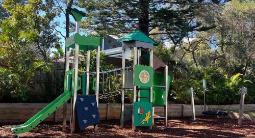 a playground with a slide in a park at Flynns on Surf Beach Villas in Port Macquarie