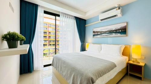 een slaapkamer met een bed met blauwe muren en een raam bij Cozy condo maikhao Phuket in Ban Mai Salae