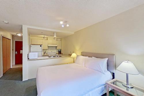 Cet appartement comprend une chambre avec un lit blanc et une cuisine. dans l'établissement Glacier Lodge, à Whistler