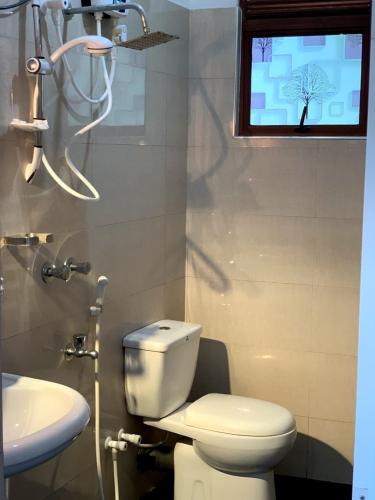 a bathroom with a toilet and a sink and a window at SILVER RAIL in Galle