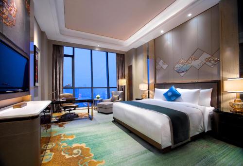 a hotel room with a large bed and a television at Wanda Vista Hohhot in Hohhot