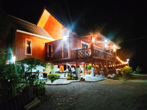 une maison avec des lumières allumées la nuit dans l'établissement ในสวนรัตนมณีรีสอร์ท, à Ban Pak Khlong