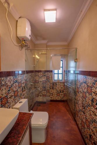 a bathroom with a toilet and a glass shower at The Ferry Cross Museotel in Panaji